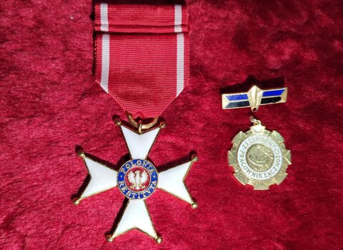 Zdjęcie przedstawia leżące Order Polonia Restituta w kształcie gwieździstego krzyża, w środku Orzeł Biały i kolisty medal.