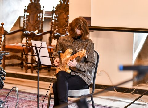 Zdjęcie. Wielka Sala Wety Ratusza Głównego Miasta. Krzysztof Hadrych wykonuje utwór na bursztynowej gitarze.  