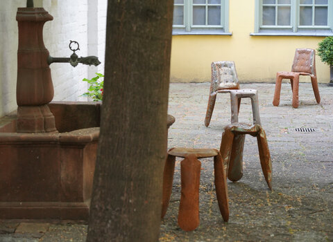 Krzesła Oskara Zięty w Domu Uphagena. Obok drzewo i dawne ujęcie wody pitnej. 