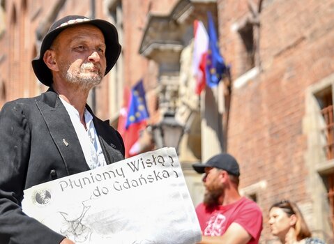 Zdjęcie. Jarosław Kałuża w góralskim stroju - inicjator Flisu Królewskiego. W tle Ratusz Głównego Miasta. 