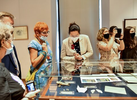 Zdjęcie. Dr Katarzyna Darecka (z lewej) oraz Aleksandra Dulkiewicz (z prawej) i inni goście oglądają eksponaty na sali wystawowej. 