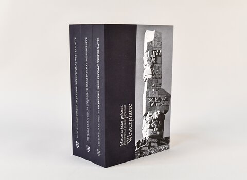 Zdjęcie. Trzy książki w kolorze granatowym stojące obok siebie, uchwycone pod katem. Na grzbietach tytuł "Historia jako pokusa. Spojrzenie przez pryzmat Westerplatte". Na okładce po prawej stronie bryła Pomnika Obrońców Wybrzeża na Westerplatte.   