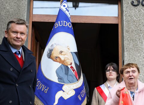 Zdjęcie przy wejściu do domu, na którego elewacji zawisła pamiątkowa tablica. Po lewej stronie stoi Waldemar Ossowski, dyrektor Muzeum Gdańska, z prawej strony stoi Maria Osińska, synowa profesora. Widać także poczet sztandarowy i sztandar szkoły, na którym znajduje się wizerunek profesora Osińskiego. 