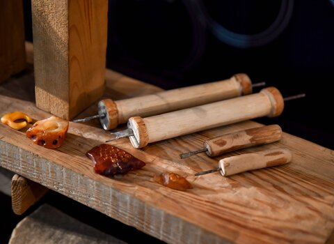 Zdjęcie. Stół. Drewniane rylce i szpikulce. Obok nich bryłki bursztynu.