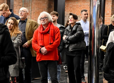 Zdjęcie. Ubrany na czerwono Andrzej Stelmasiewicz - gdański radny. Obok niego goście wernisażu.  