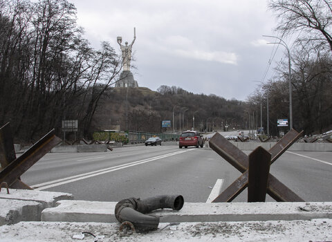 Kijów w marcu 2022. W tle jeden z najbardziej znanych symboli miasta. 62. metrowy Pomnik Matki Ojczyzny, górujący nad Muzeum Historii Ukrainy w II Wojnie Światowej. Na ulicy jeże przeciwczołgowe. 