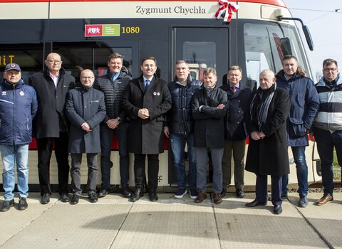 Wspólne zdjęcie uczestników uroczystości. W tle tramwaj im. Z. Chychły. 