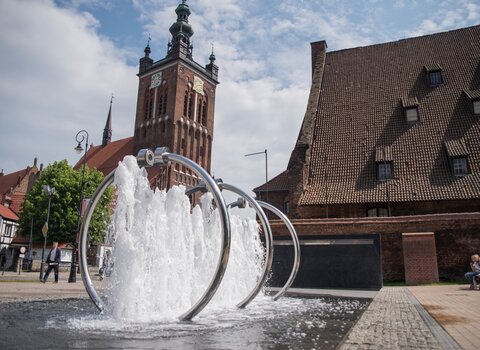 Zdjęcie. Od lewej, Kościół św. Katarzyny i Wielki Młyn. Przed nimi Fontanna Heweliusza. 