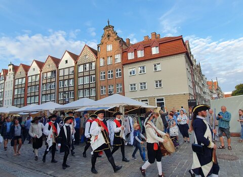 Parada podczas 759. Jarmarku św. Dominika. Na tle zabudowań maszerują trębacze przebrani w historyczne stroje. 