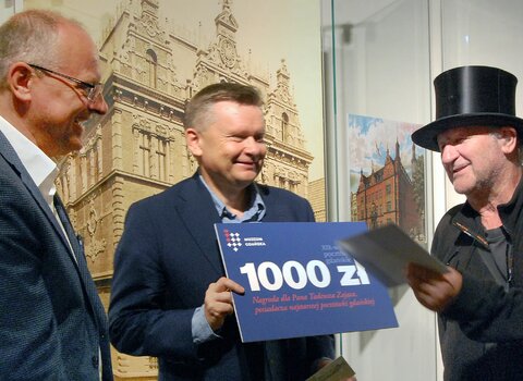 Tadeusz Zając (po prawej), otrzymuje z rąk Waldemara Ossowskiego (w środku) nagrodę w wysokości 1000 zł. 