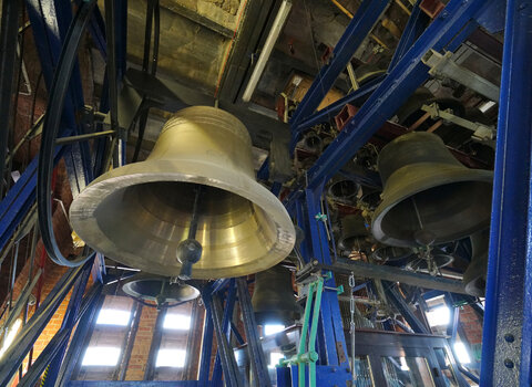 Zdjęcie wykonane w wieży kościoła św. Katarzyny (Muzeum Nauki Gdańskiej). Widok na zespół dzwonów – carillon, zawieszony na stalowej konstrukcji. Na pierwszym planie widoczny od dołu jeden z dzwonów. 