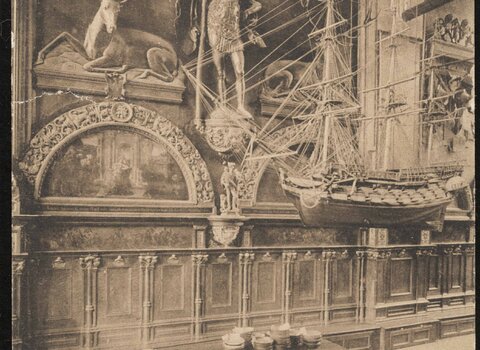 Pocztówka w tonacji sepii ukazuje wnętrze Dworu Artusa - widok na Ławę Bractwa św. Krzysztofa. W centrum, pod rzeźbą św. Krzysztofa, widoczna niewielka rzeźba Saturna. 