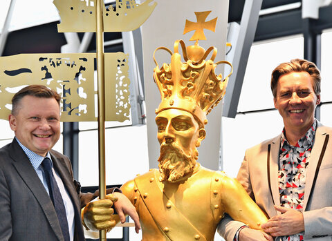 Zdjęcie. Waldemar Ossowski i Tomasz Kloskowski stoją obok rzeźby króla Zygmunta Augusta (w centrum). 