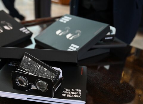Zdjęcie. Na stole leżą trzy egzemplarze albumu. Zestaw składa się z pudełka, albumu w formie książki, okularów do samodzielnego złożenia oraz zestawu 16 zdjęć do oglądania w technologii stereoskopowej.
