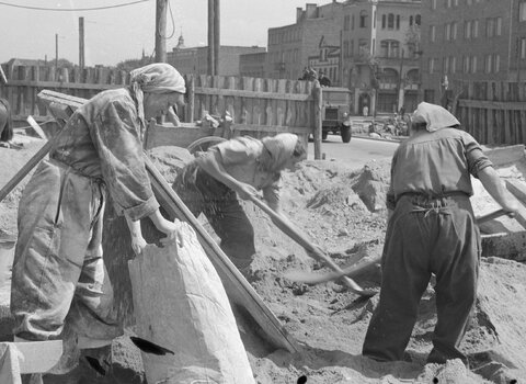 Ekipa kobieca kierowana przez Rozalię Bober podczas budowy GDM-u, po prawej widoczna kamienica z narożnym wykuszem w formie wieżyczki, 1951, zb. NAC