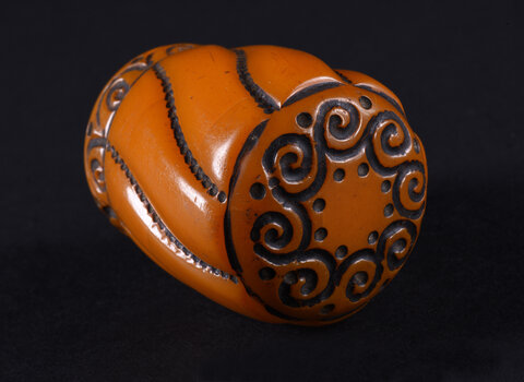 Gałka do laski w formie obłego, lekko zwężającego się ku dołowi walca, o dwóch podstawach w formie koła. Gałka rozczłonkowana po obwodzie przez esowate linie utworzone przez gęsto ułożone kropki. Górna podstawa dekorowana w koło ornamentem pojedynczych, połączonych ze sobą spirali, przy łączeniu ujętych po bokach dwoma kropkami. Dolna partia gałki dekorowana wąskim fryzem z ornamentem tworzonym przez szereg pojedynczych spirali w półłuku, między półłukami pojedyncza kropka.