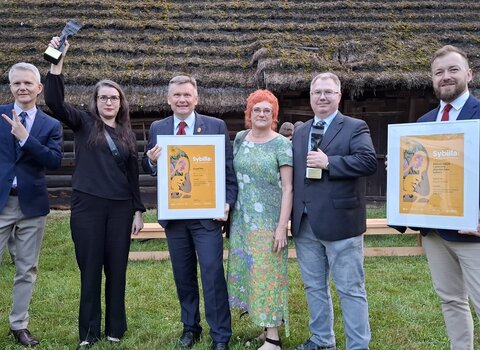 Od lewej: Janusz Marszalec (obecnie Muzeum II Wojny Światowej), Kinga Krause, Waldemar Ossowski, Katarzyna Darecka, Tomasz Wierzchowski oraz Maciej Flis. W tle chata pokryta strzechą. 