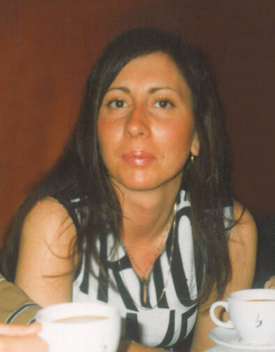 Zdjęcie przedstawia młodą, uśmiechniętą brunetkę w koszuli w czarno-białe pasy patrzącą w obiektyw. 