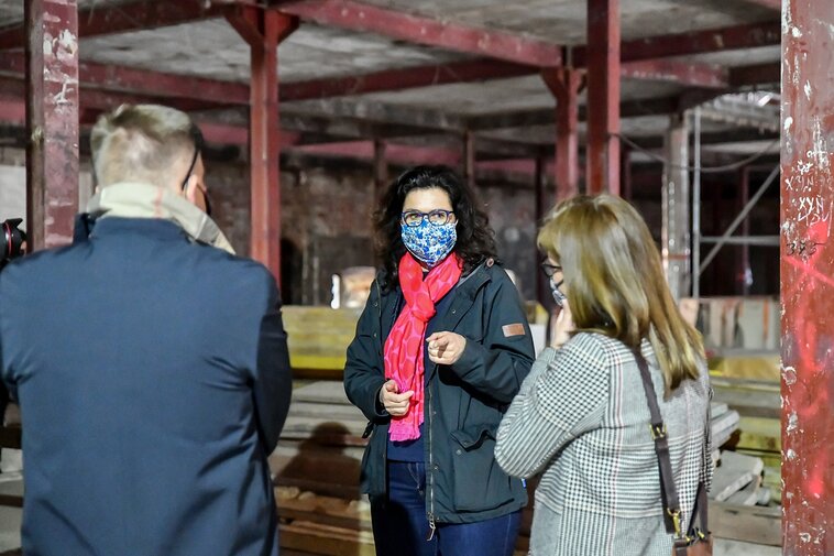 Zdjęcie przedstawia prezydent Gdańska Aleksandrę Dulkiewicz (od przodu) rozmawiającą z Waldemarem Ossowskim oraz Barbarą Frydrych. W tle metalowe słupy i rusztowania.  