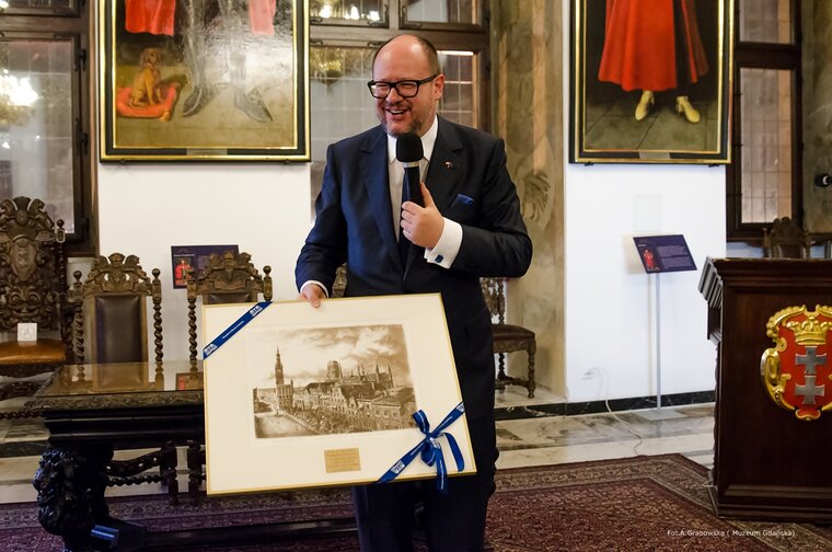 Spotkanie w Wielkiej Sali Wety Ratusza Głównego Miasta (22.11.2018) z okazji przekazania przez prof. Wolfganga Deurera 1212. negatywów dokumentujących detale architektoniczne zabytków przedwojennego Gdańska. W centrum śp. Prezydent Adamowicz trzyma w dłoni obraz w ramce z panoramą dawnego Gdańska. 