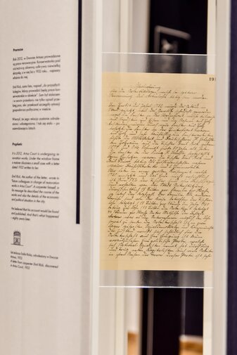 Zdjęcie przedstawia list zapisany w języku niemieckim zabezpieczony z dwóch stron szkłem.  