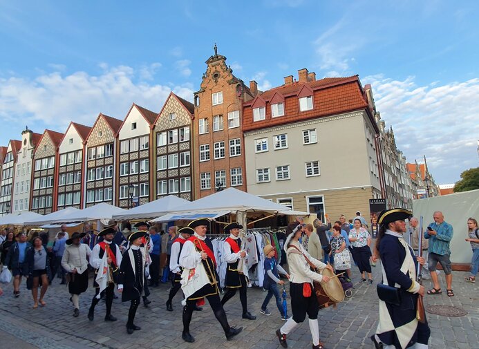 Parada podczas 759. Jarmarku św. Dominika. Na tle zabudowań maszerują trębacze przebrani w historyczne stroje. 