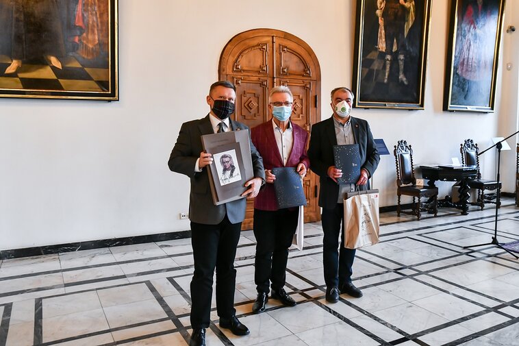 Na zdjęciu od lewej Waldemar Ossowski, dyrektor Muzeum Gdańska, Karol Klukowski oraz Jacek Borzych z egzemplarzem Teki Gdańskiej oraz pakietami Darczyńcy Muzeum Gdańska w Wielkiej Sali Wety Ratusza Głównego Miasta, w tle obrazy i drzwi. 