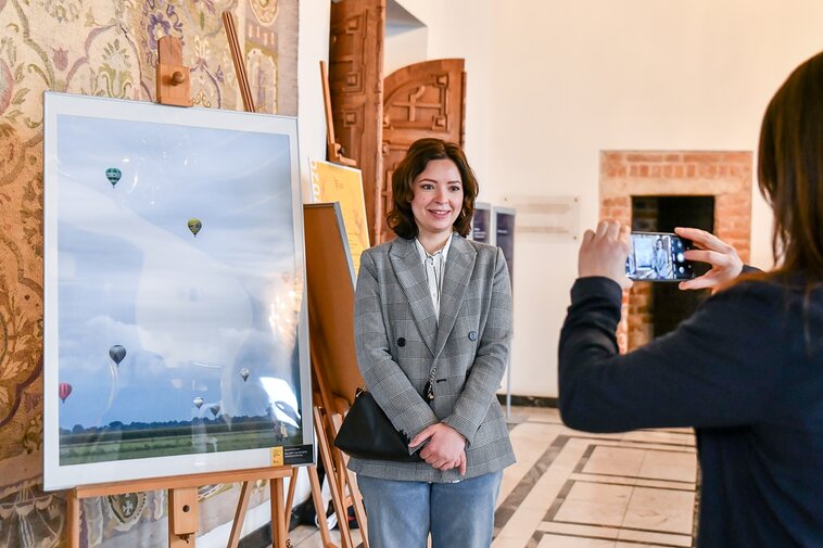 Na zdjęciu Agnieszka Giętkowska, laureatka III miejsca w kategorii Wydarzenia z życia miasta. Obok niej na sztaludze fotografia ze wzlatującymi w niebo balonami.   