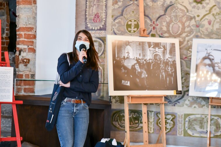 Na zdjęciu Tamara Kanecka-Brzóska opowiada o historii wykonanego przez nią zdjęcia w trakcie Strajku Kobiet pod Katedrą Oliwską. Obok zdjęcie w skali szarości przedstawiające protest obrońców Kościoła pod Katedrą Oliwską.  