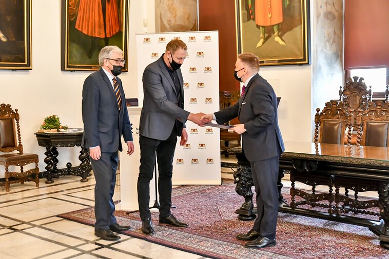 Zdjęcie. Wielka Sala Wety Ratusza Głównego Miasta. Zbigniew Strzelczyk (pierwszy z lewej) i Andrzej Gielo (drugi z lewej) otrzymują Medal Muzeum Gdańska od Waldemara Ossowskiego (z prawej).