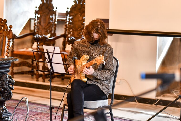 Zdjęcie. Wielka Sala Wety Ratusza Głównego Miasta. Krzysztof Hadrych wykonuje utwór na bursztynowej gitarze.  
