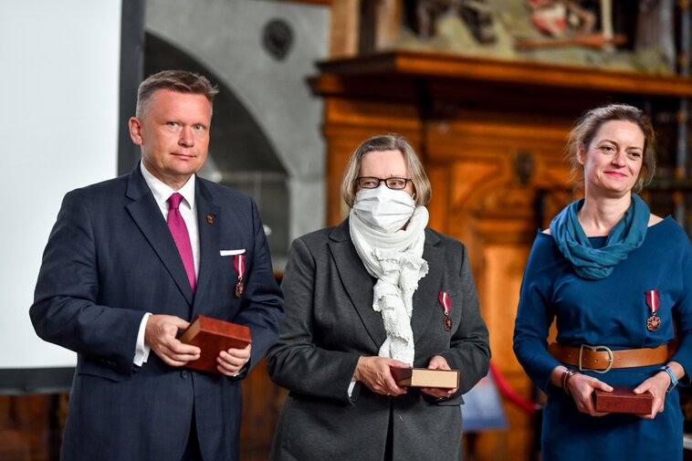 Od lewej Waldemar Ossowski, Ewa Szymańska oraz Monika Kaźmierczak trzymają w dłoniach odznaczenia Gloria Artis. 