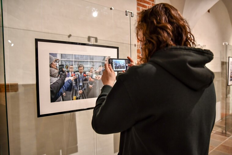 Uczestnik wernisażu wykonuje zdjęcie fotografii prezentowanej na wystawie. 