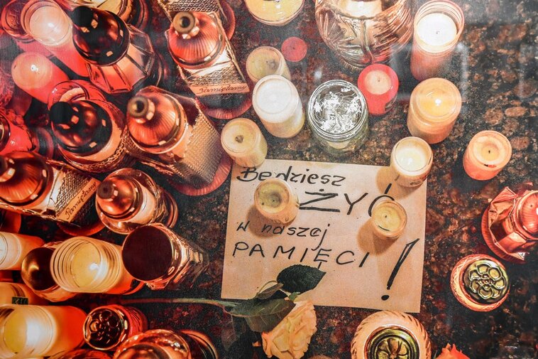 Zdjęcie jednej z fotografii prezentowanych na wystawie. Znicze. Pod nimi karta z napisem "Będziesz żyć w naszej pamięci". 