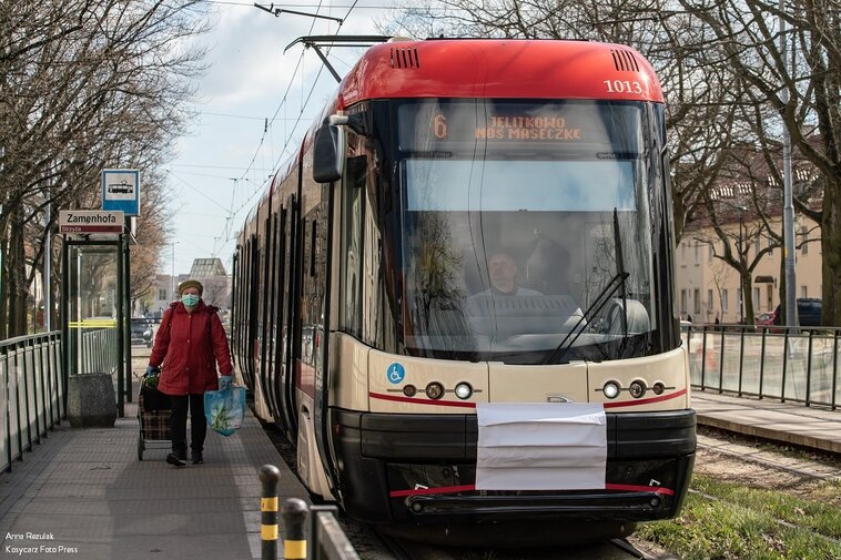 Zdjęcie. Tramwaj z maseczką na dziobie. Obok przystanek na ulicy Zamenhofa na gdańskiej Strzyży. 