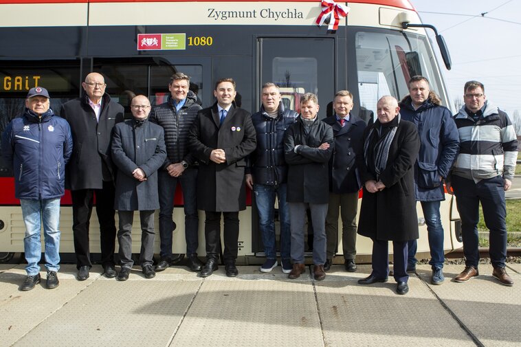 Wspólne zdjęcie uczestników uroczystości. W tle tramwaj im. Z. Chychły. 