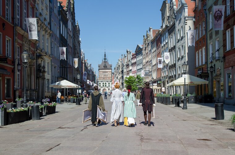 Zdjęcie. Ul. Długa w kierunku Zespołu Przedbramia. Ulicą idą osoby przebrane w historyczne kostiumy. 