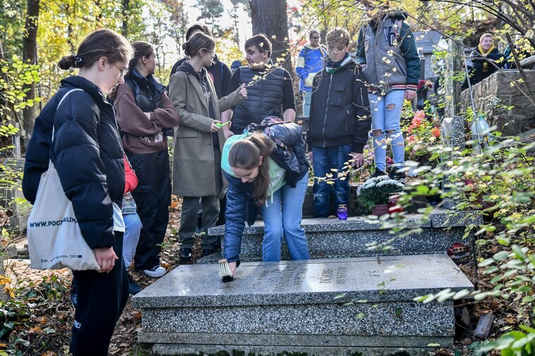 Podczas akcji uczniowie sprzątają groby członków Armii Krajowej. 