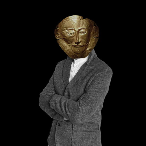 Zdjęcie. Na czarnym tle sylwetka człowieka. Zamiast twarzy ma złotą maskę Agamemnona. 