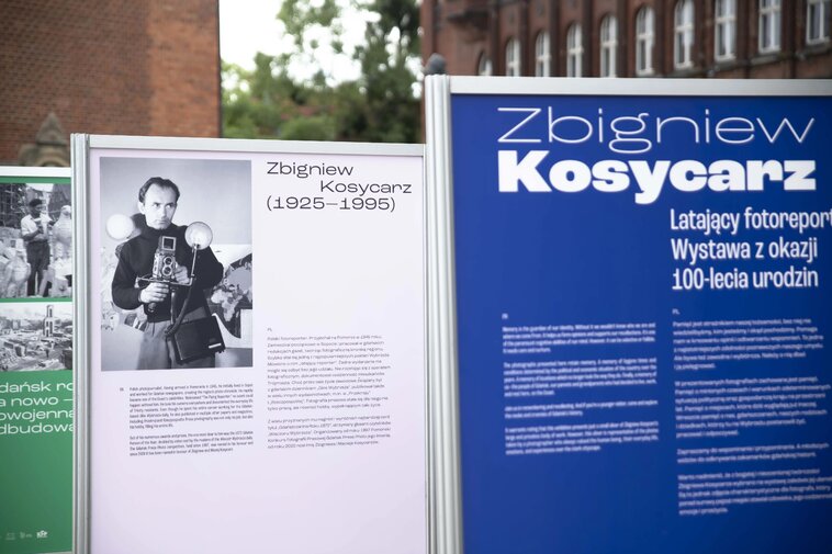 Plansze wystawy. Na zdjęciu plansza tytułowa oraz wizerunek fotoreportera z aparatem w rękach.  