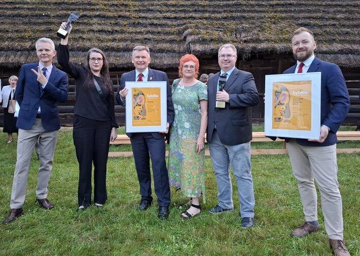 Od lewej: Janusz Marszalec (obecnie Muzeum II Wojny Światowej), Kinga Krause, Waldemar Ossowski, Katarzyna Darecka, Tomasz Wierzchowski oraz Maciej Flis. W tle chata pokryta strzechą. 
