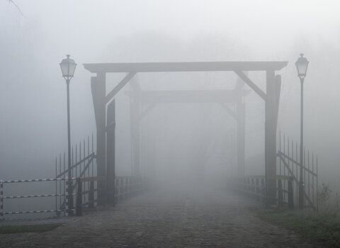 Zdjęcie przedstawia drewniany most prowadzący na Szaniec Wschodni Twierdzy Wisłoujście. Zdjęcie zrobione od strony wejścia na most w mglisty poranek. 