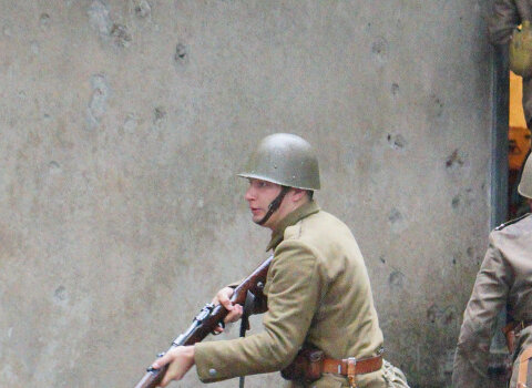 Zdjęcie przedstawia rekonstrukcję walk w obronie Westerplatte 1-7 września 1939 r. Widocznych kilku rekonstruktorów w polskich mundurach wbiegających do budynku wartowni. 