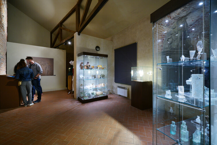 Zdjęcie przedstawia wnętrze Domu Komendanta w Twierdzy Wisłoujście. Po prawej widać trzy szklane gabloty zawierające przedmioty z dawnego wyposażenia pomieszczenia.
