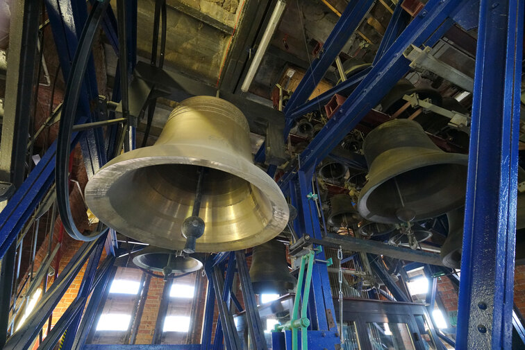 Zdjęcie wykonane w wieży kościoła św. Katarzyny (Muzeum Nauki Gdańskiej). Widok na zespół dzwonów – carillon, zawieszony na stalowej konstrukcji. Na pierwszym planie widoczny od dołu jeden z dzwonów. 