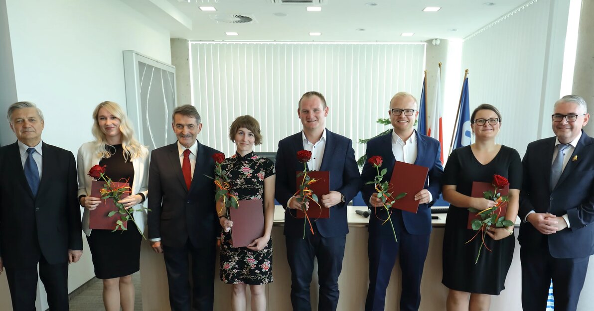 Na zdjęciu pozują laureaci nagrody wraz z przedstawicielami Polskiego Towarzystwa Naukowego i Piotra Kowalczuka, zastępcy prezydenta ds. edukacji i usług społecznych. Osoby na zdjęciach są elegancko ubrane, stoją w rzędzie. Laureaci nagrody trzymają w rękach dyplomy i czerwone róże. 