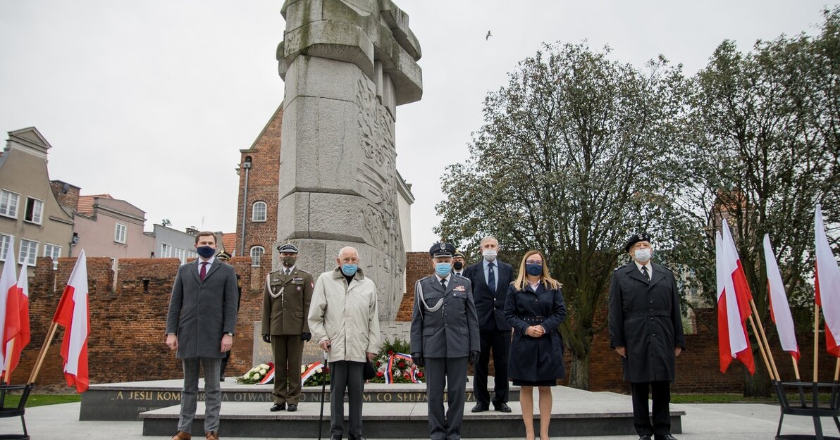 Na zdjęciu znajdują się osoby upamiętniające w Gdańsku Czyn Bojowy Polskich Sił Zbrojnych na Froncie Wschodnim. Stoją na stopniach przed pomnikiem Tym, co za polskość Gdańska. Pozują do zdjęcia ustawieni przodem do aparatu. Na twarzach mają maseczki. (od lewej) Piotr Grzelak - Zastępca Prezydenta Miasta Gdańska, Pułkownik Piotr Piątkowski, cz. p. o. Szefa 17. Terenowego Oddziału Lotniskowego, Roman Rakowski - Komandor w stanie spoczynku - Prezes Honorowy Związku Inwalidów Wojennych, Stanisław Skrzypski - Prezes Zarządu Okręgowego Związku Inwalidów Wojennych, Agnieszka Owczarczak - Przewodnicząca Rady Miasta Gdańska, Major Edmund Popieliński - Sekretarz Zarządu Wojewódzkiego w Gdańsku Ogólnokrajowego Stowarzyszenia Kombatantów Polskich Sił Zbrojnych na Zachodzie.
