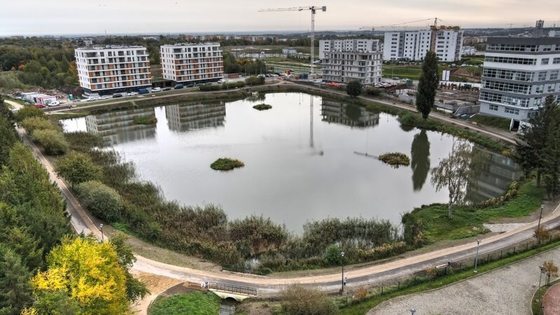 Na zdjęciu widoczny jest zbiornik wodny Jabłoniowa, widok z góry. Widoczna jest też ścieżka wokół zbiornika oraz bloki mieszkalne w tle.