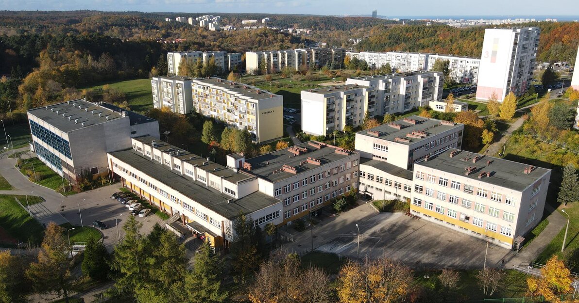 Zdjęcie z lotu ptaka, widoczny jest cały kompleks budynków szkolnych. W tle pobliskie bloki i wieżowce. 