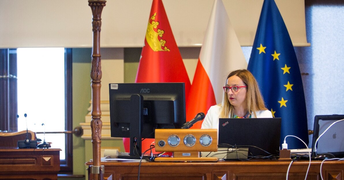 Za biurkiem w Sali obrad, przed dwoma monitorami – komputera oraz laptopa – siedzi przewodnicząca Rady Miasta Agnieszka Owczarczak. Za nią widać trzy flagi w stojakach: Gdańska, Polski oraz Unii Europejskiej. Fot. Renata Dąbrowska